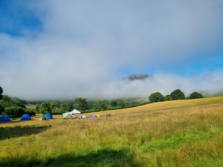 A sunny morning looking over tents with misty clouds